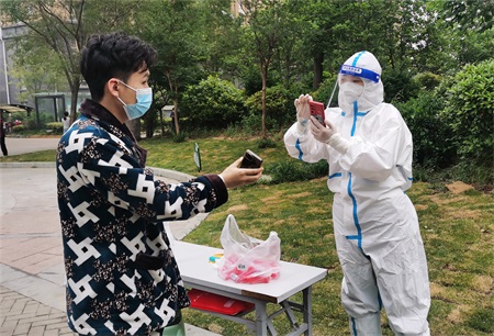 图1：汇聚微力，那些温暖至深的力量。面对复杂严峻的疫情防控形势，河南交通投资集团中原高速郑漯分公司坚持人民至上、生命至上，勠力同心、并肩战疫。居家办公党员就地转化为社区志愿者，用爱心与行动守护人民群众的生命安全和身体健康。图为“验码大白”在社区进行检测码登记工作。王小东摄.jpg